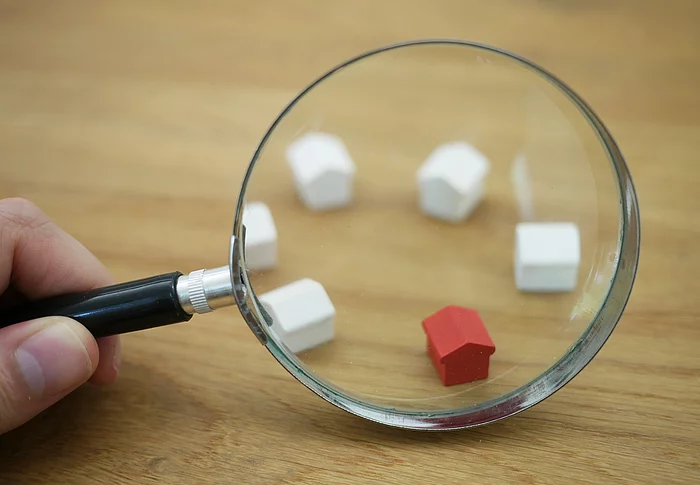 Symbolbild: Kleine Häuser unter einer Lupe